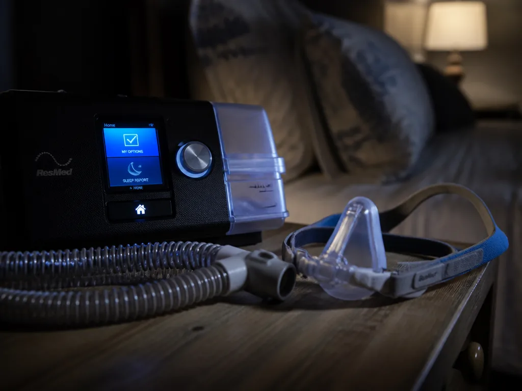 A close-up nighttime photograph of a CPAP machine and heated humidifier tub resting on…