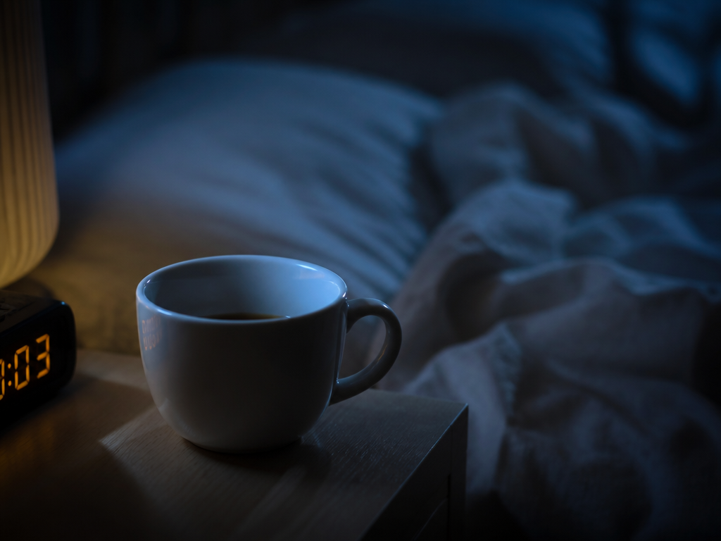 A close-up photorealistic still life of a white ceramic coffee cup sitting on a…